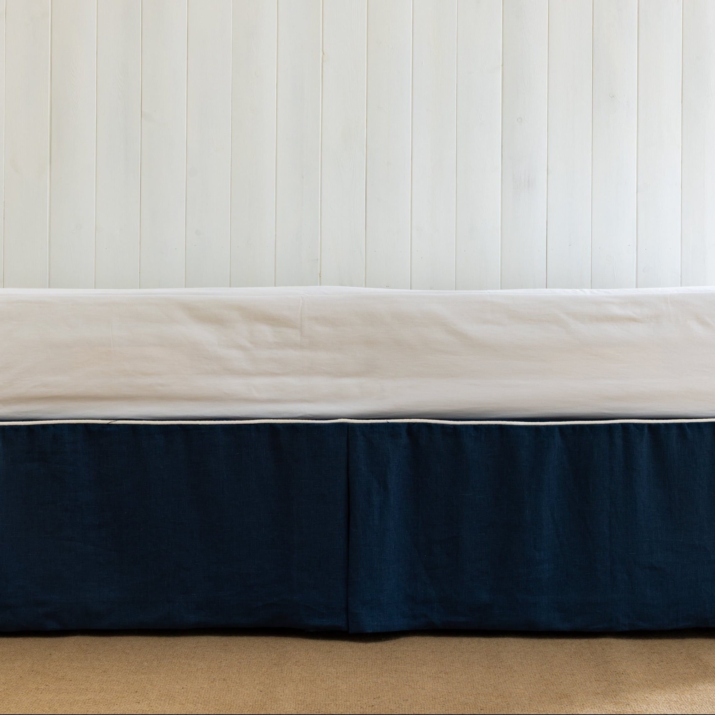 Bed with a navy blue bed skirt or bed valance in blue linen