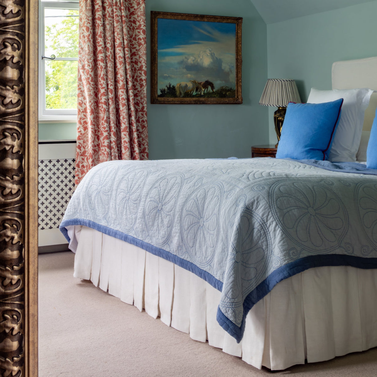 Bedroom with light blue walls, floral curtains, and a Beata Heuman bedspread