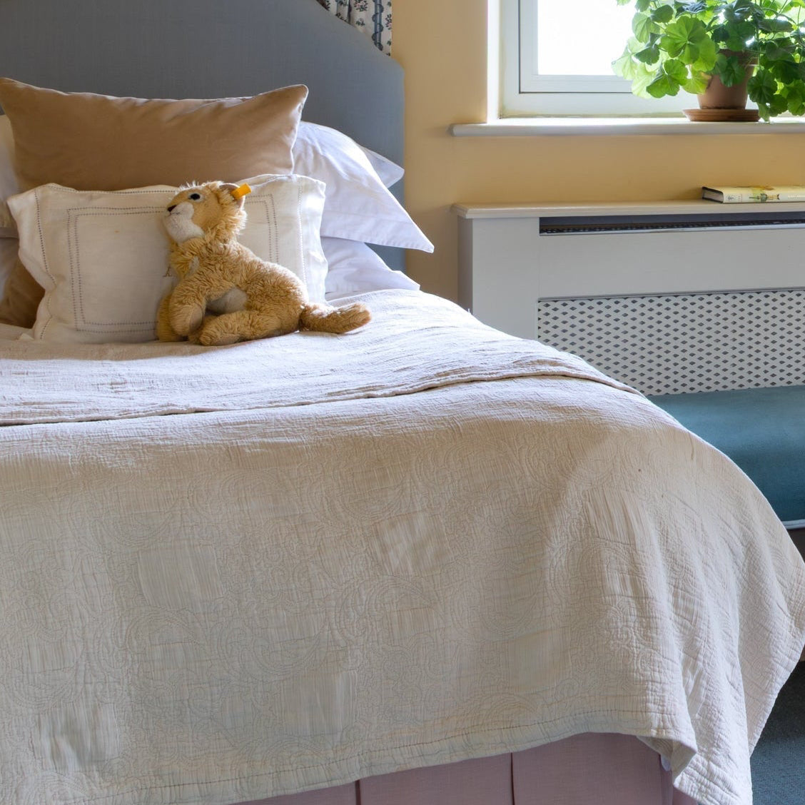 Two beds in a bedroom with yellow walls, a window, and decorative items. Bed Valances in Pink and Teal. Children's twin bedroom.