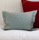 Three decorative pillows in red, gray, and green on a white surface with a wooden panel background.