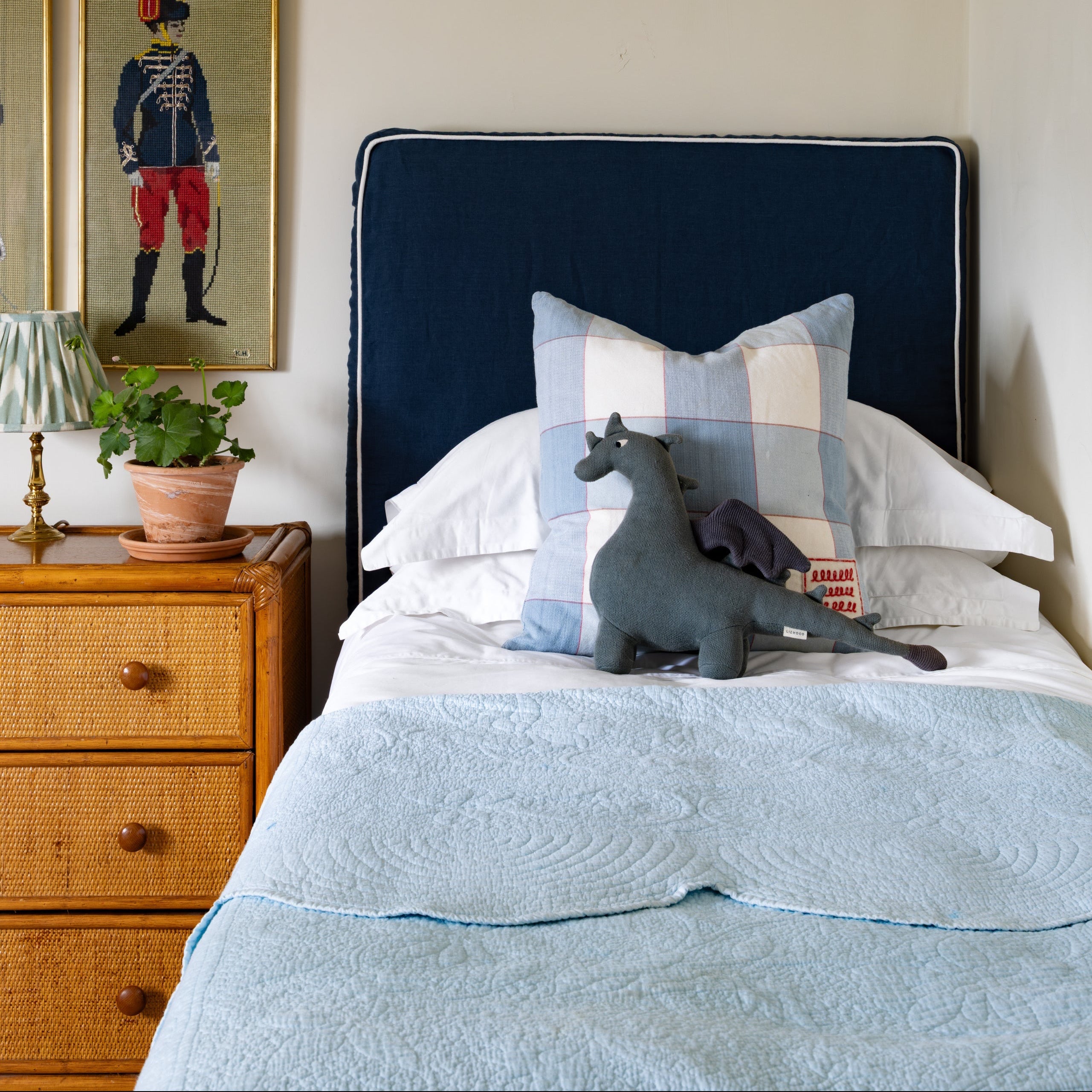 Child's Bedroom with a bed featuring pillows and a stuffed animal, a wooden nightstand with a lamp, and framed artwork on the wall.