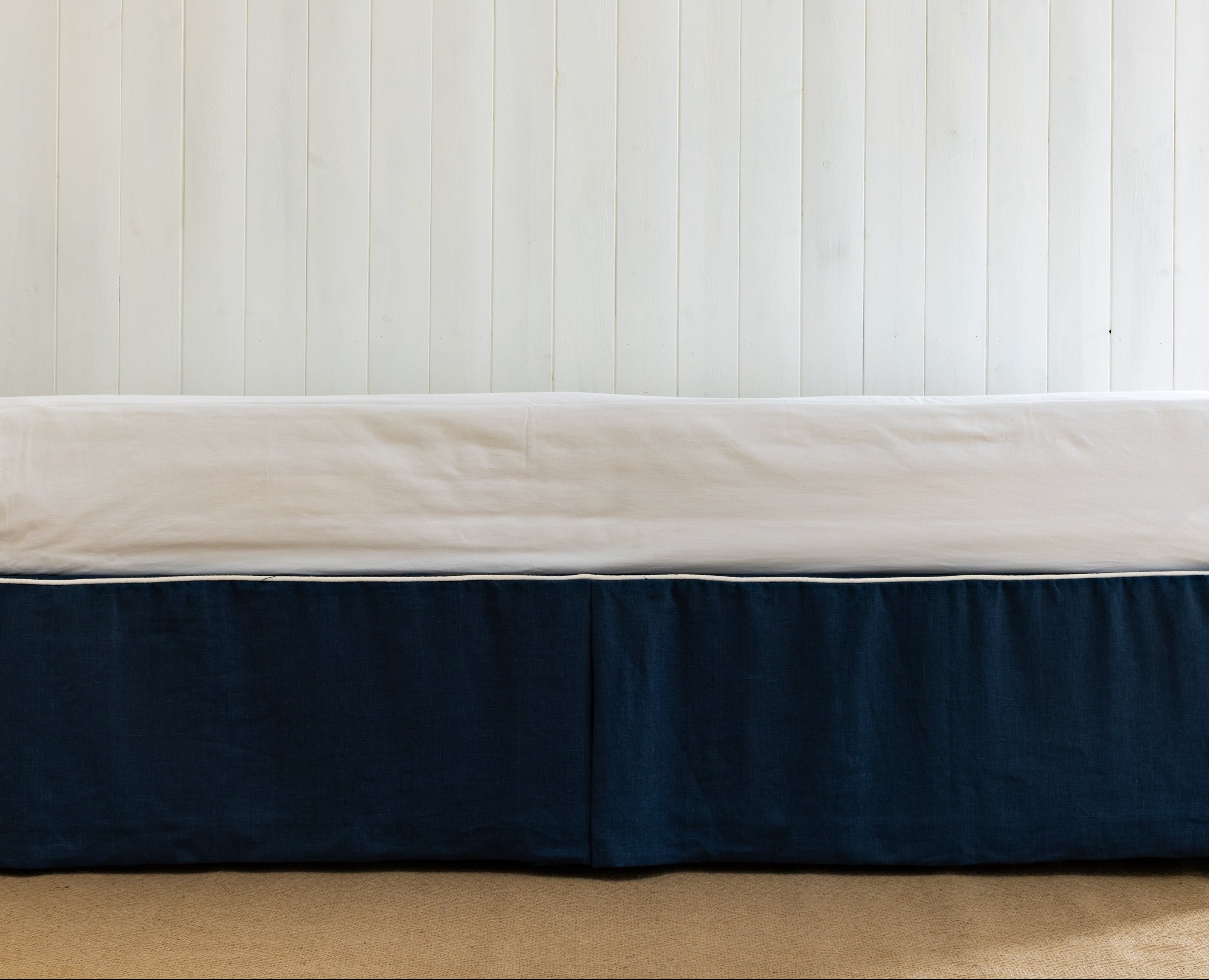 Bed with a navy blue bed skirt or bed valance in blue linen