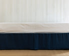 Bed with a navy blue bed skirt or bed valance in blue linen