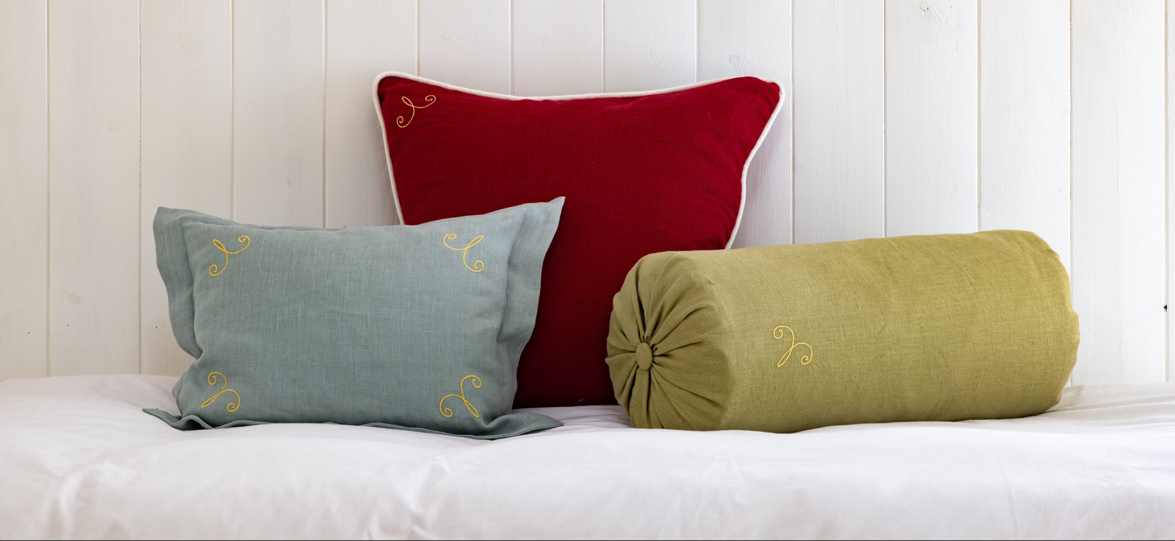 Three decorative pillows in red, blue, and green on a white surface