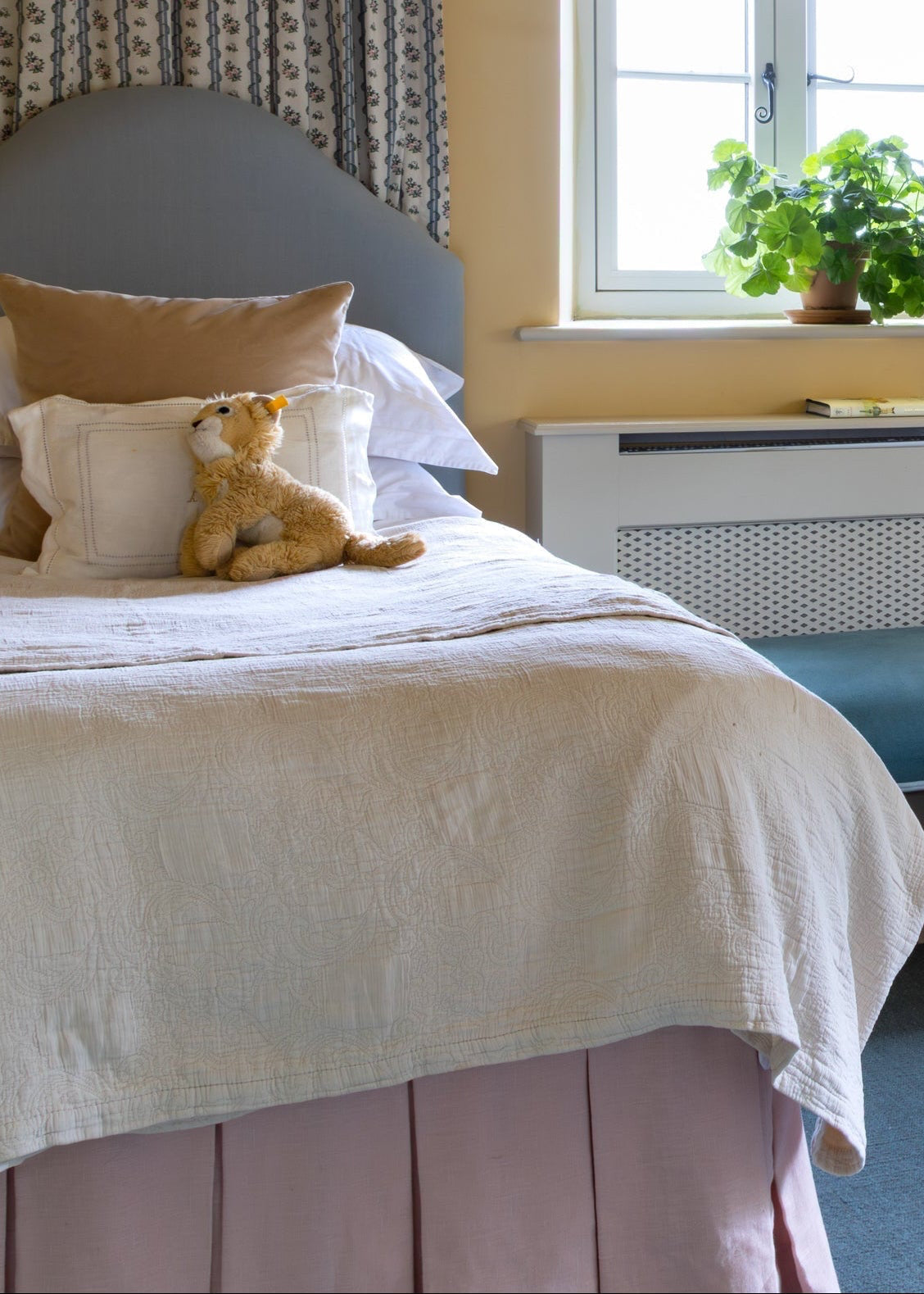Two beds in a bedroom with yellow walls, a window, and decorative items. Bed Valances in Pink and Teal. Children's twin bedroom. 